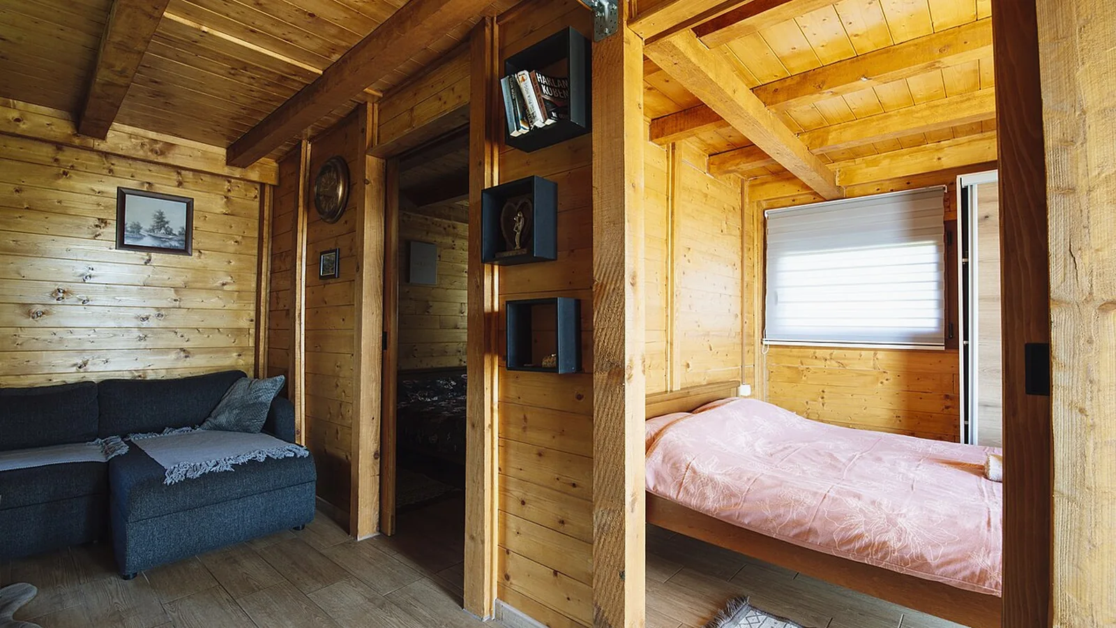 Intérieur chaleureux en bois avec canapé et espace nuit éclairé par la lumière naturelle